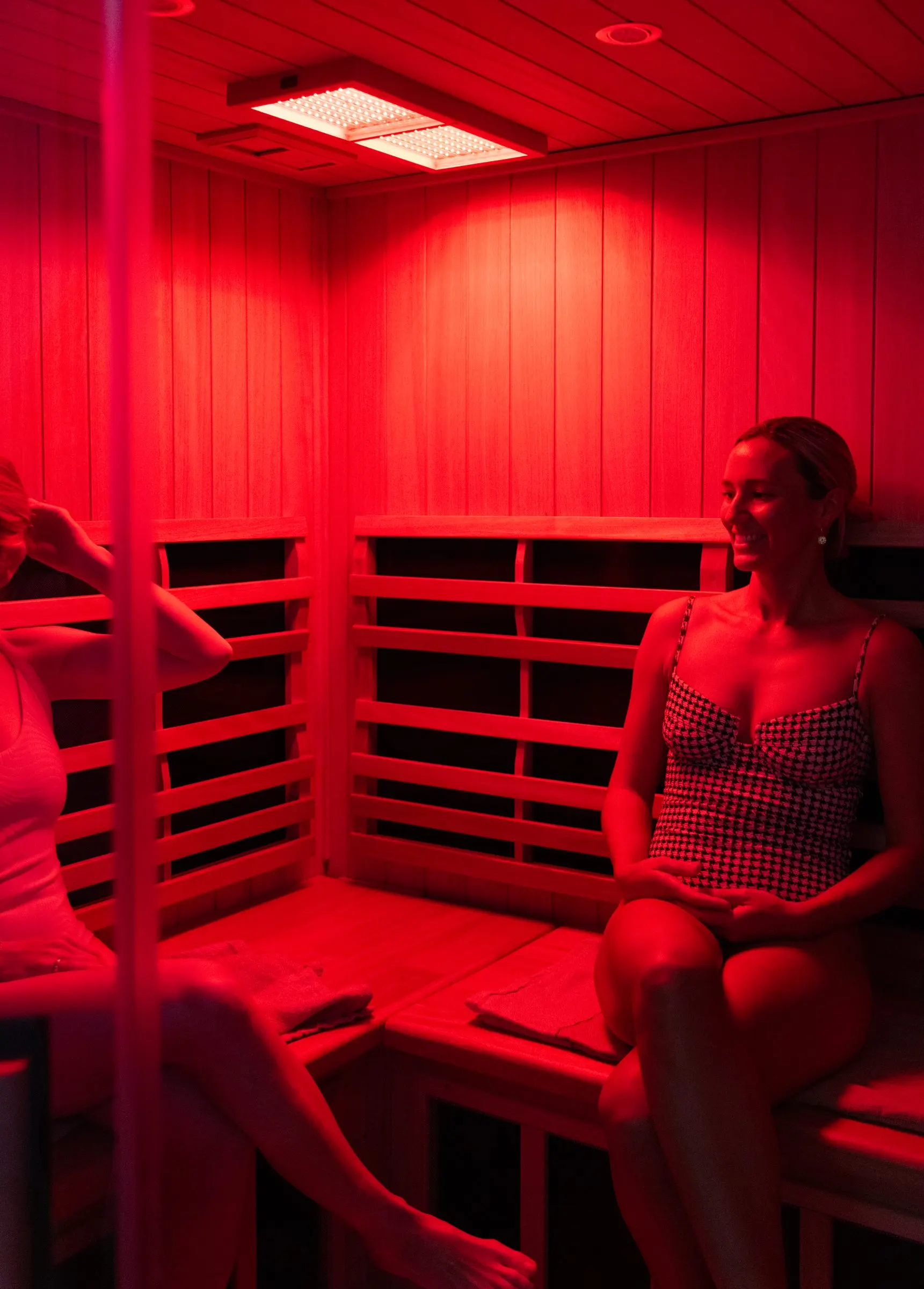 Two members inside the infrared sauna under red light